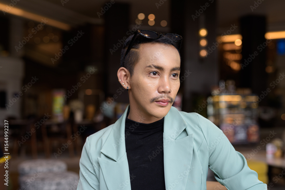 Fototapeta premium Portrait of nonbinary genderfluid young Asian gay man in cafe