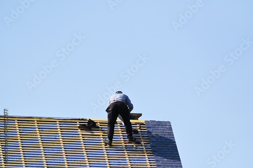 ouvrier couvreur sur un toit d'habiation en cours de rénovation