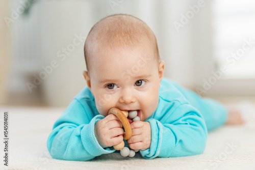 Baby chewing teething ring while lying down. Tummy time