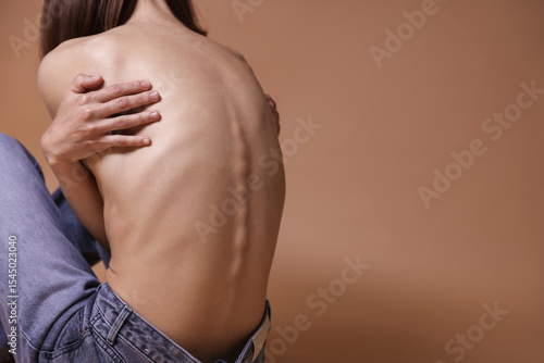 Woman suffering from anorexia on dark beige background, closeup. Space for text