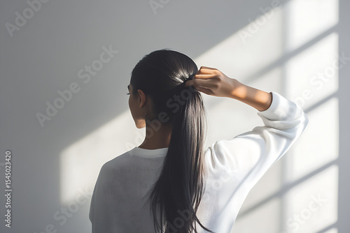 Side View of Woman Tying Hair Back, Minimal White Backdrop