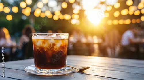 Iced Coffee with Cream on Wooden Table at Outdoor Cafe at Sunset