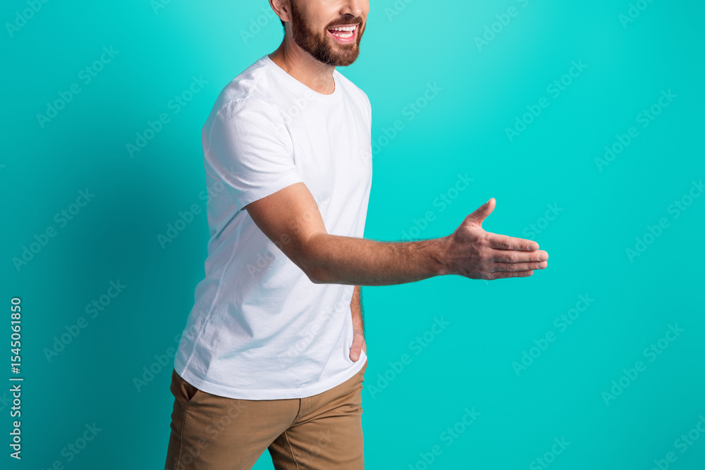 Fototapeta premium Smiling man extends hand for a handshake against a teal backdrop wearing casual fashion showcasing a friendly gesture
