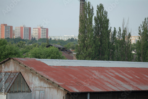 Wallpaper Mural A weathered, rusty roof atop an old building stands prominently against a sprawling city skyline in the background, showcasing urban life Torontodigital.ca