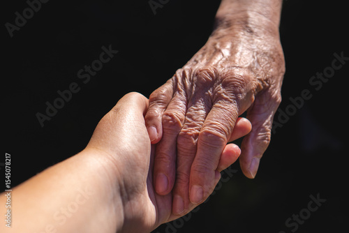 Φωτογραφία Touching Hands of Two Generations on a Black Background