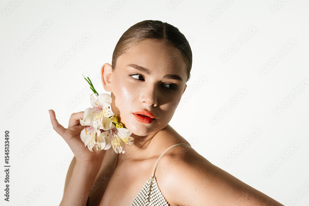 Fototapeta premium Sensual woman on isolated background with flower in hands. Cosmetology, make-up and spa concept.