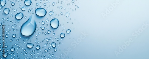 Isolated water droplets on a wet window glass with a soft blue background and clear textures