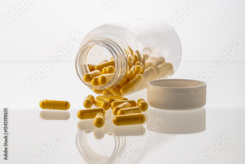 A jar with pills inside lies on a white background with reflection. Hyaluronic acid, collagen, vitamins or barberry for losing weight. Medical preparations for health and beauty. Copyspace.
