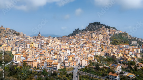Foto Hilltop town with rocky cliff and many buildings under tiled roofs on sunny day,