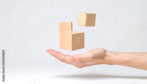 Hand balancing wooden blocks on white.