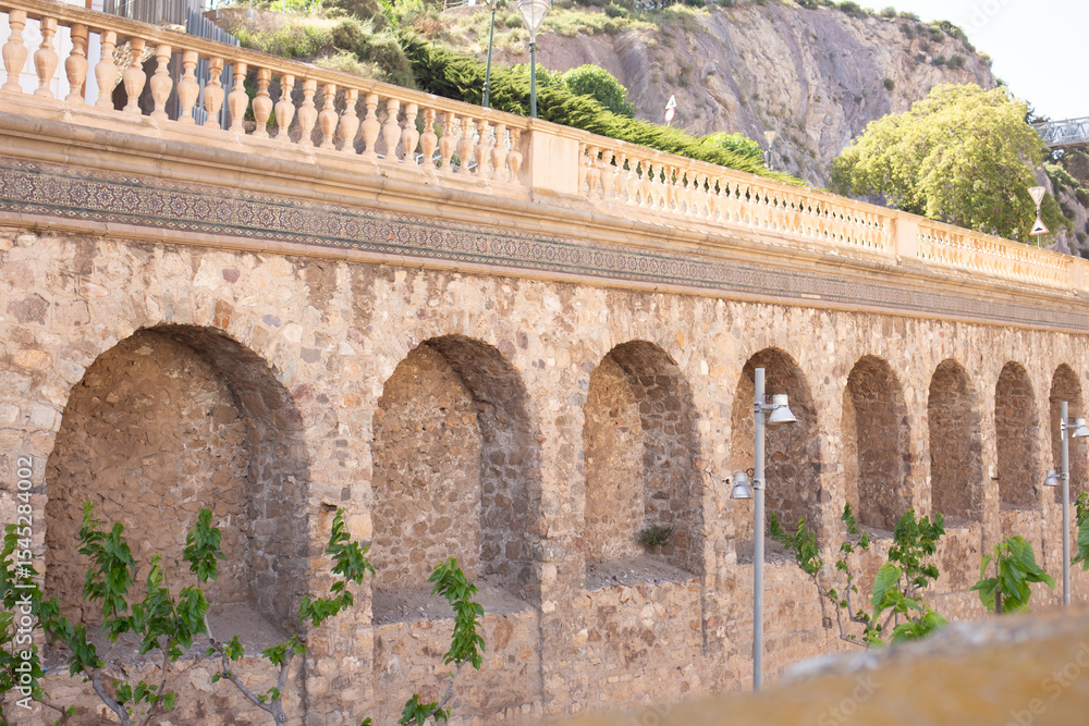 Fototapeta premium Historic stone archways along a scenic pathway in Spain ideal for travelers exploring the region