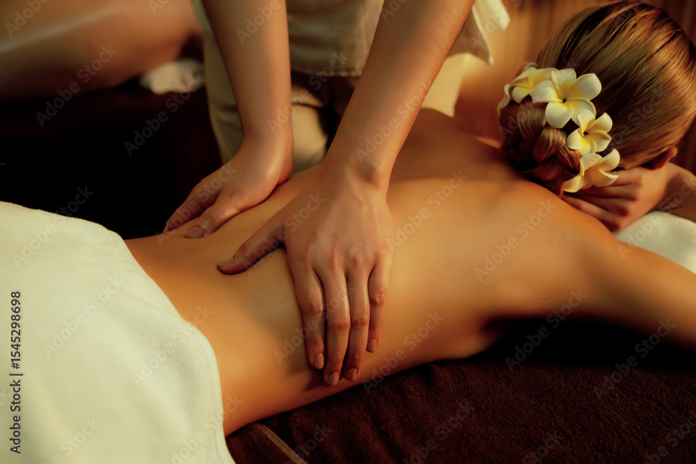 Fototapeta premium Closeup couple customer enjoying relaxing anti-stress spa massage and pampering with beauty skin recreation leisure in warm candle lighting ambient salon spa at luxury resort or hotel. Quiescent