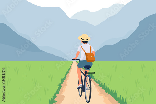 Rear view of a woman riding a bicycle through a rice field or paddy in the countryside of a village on holiday. A tourist using a bike as sustainable transport for slow travel on a summer vacation
