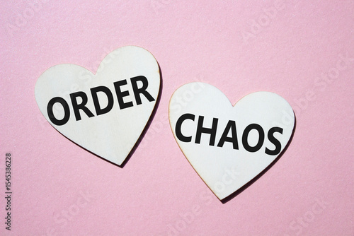 Chaos or Order symbol. Concept word Chaos or Order on wooden hearts. Beautiful pink background. Business and Chaos or Order concept. Copy space