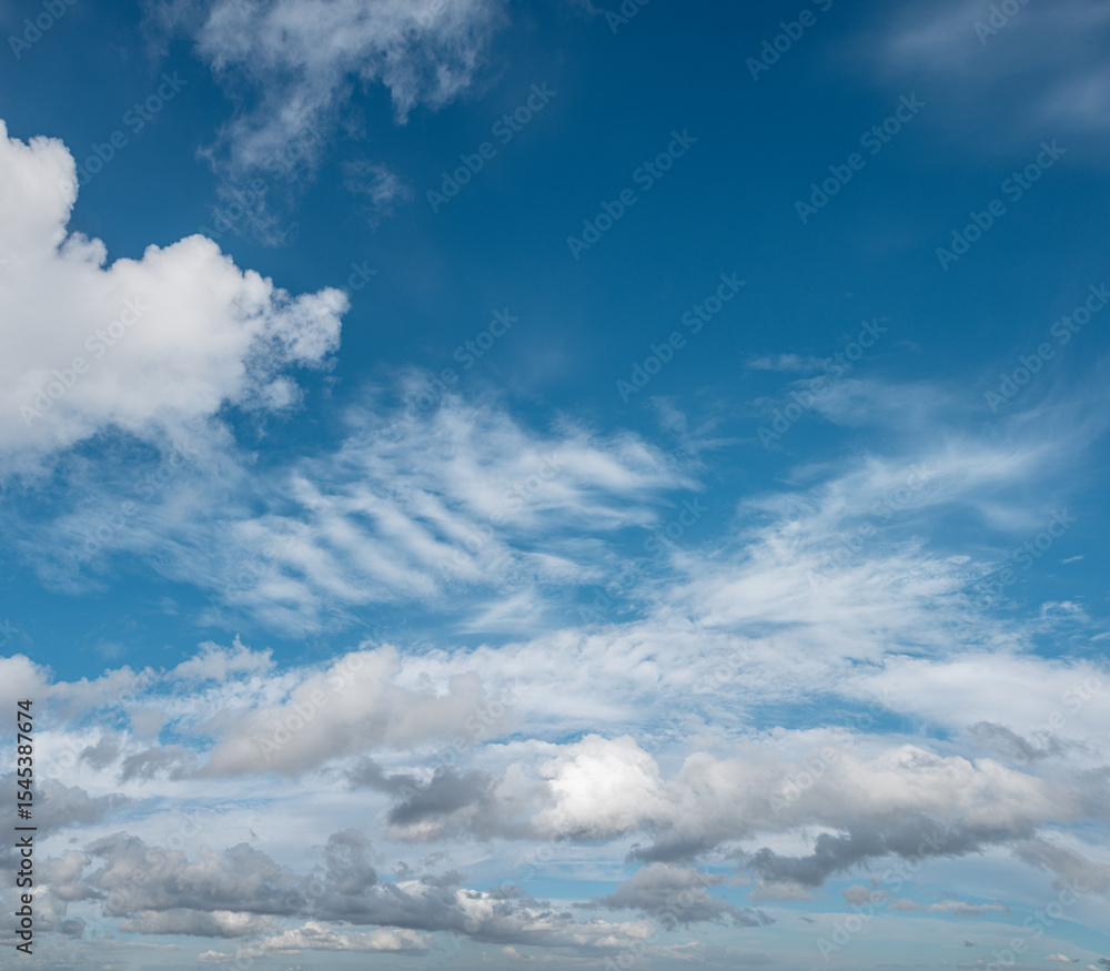 Fototapeta premium Sky panorama filled with a variety of clouds, from fluffy cumulus to wispy cirrus, stretches across the horizon on a bright