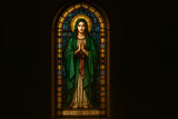 Stained Glass Window Depicting Saint Mary with Halo and Praying Hands in a Traditional Church Setting Illuminated by Soft Light