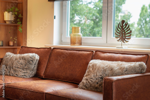 Modern luxury living room corner with a brown leather sofa, warm ambient wall lighting, minimalist decor, and stylish contemporary furniture in a cozy apartment interior.
