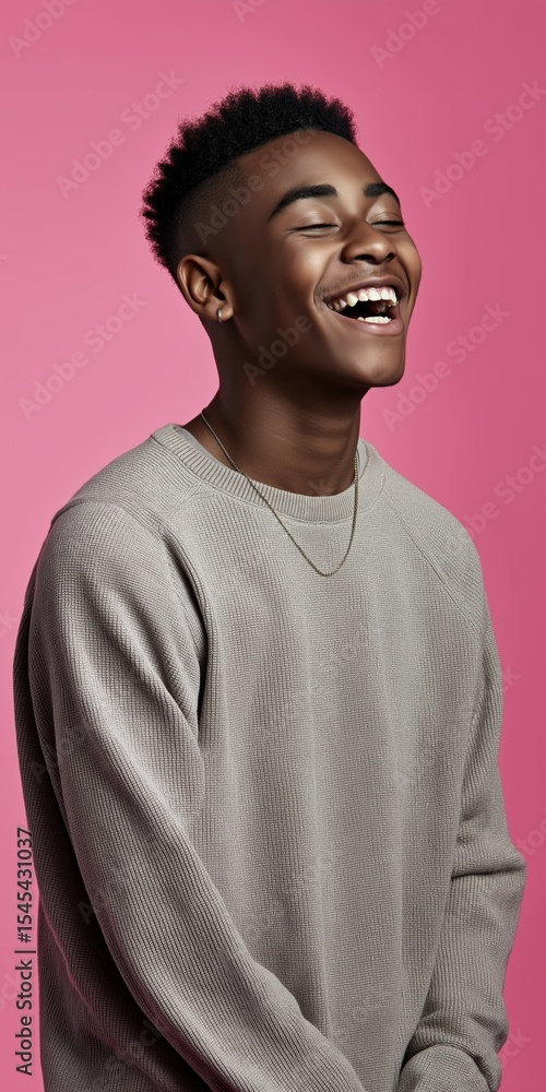 A man with a shaved head is smiling and laughing. He is wearing a gray sweater and a necklace A man with a shaved head is smiling and laughing. He is wearing a gray sweater and a necklace
