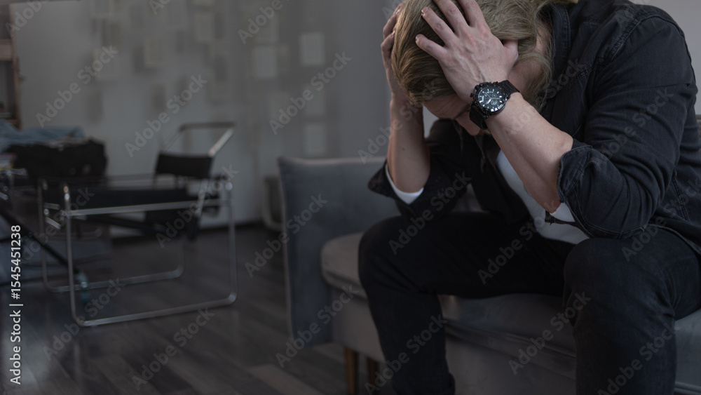 Αυτοκόλλητο A man in deep depression and apathy, sitting on the couch with his head in his h
