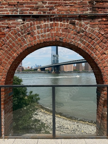 view of boat, bridge and river through a red brick archway