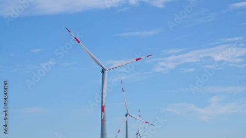 Close up, crop rotation of blades of wind turbine against background of blue sky with clouds in background. Concept of environmentally friendly energy production, wind power plant.