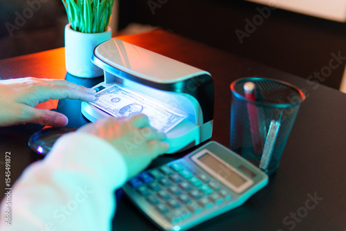 Cashier checking dollar banknote authenticity using detector machine