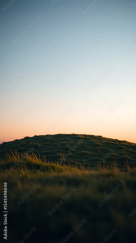 Obraz premium Rounded Grassy Knoll at Dusk Under Soft Light vertical