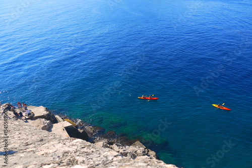 view over beautiful cerulean ocean with attracting red kayaks in a sunny day, Adriatic Sea, Dubrovnik, Croatia