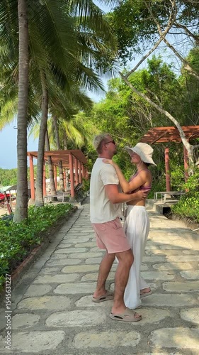 A beautiful girl and a guy in white trousers are walking. The man is twirling his beloved in his arms. Lifts the girl upwards. Slow motion. Lovers walking along the ocean coast against the background 