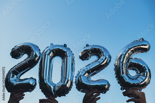 Happy new year 2026 metallic balloons on blue sky background. Greeting card silver foil balloons numbers Christmas holiday concept. Celebration party congratulation decoration