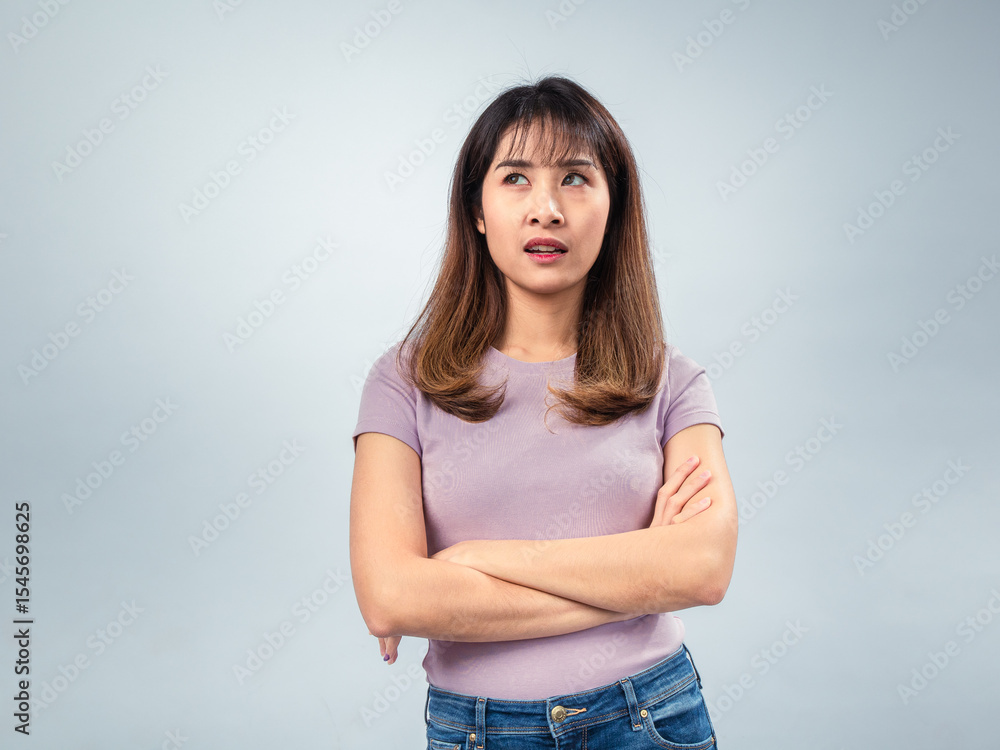 Asian woman standing with arms crossed, wearing a purple t-shirt and jeans, showing a serious and confident expression against a soft gradient background Asian woman standing with arms crossed, wearing a purple t-shirt and jeans, showing a serious and confident expression against a soft gradient background
