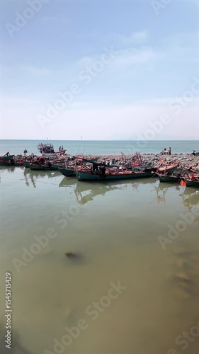 Wallpaper Mural Several traditional wooden fishing boats are moored in a line alongside a rugged, rocky shore. Torontodigital.ca