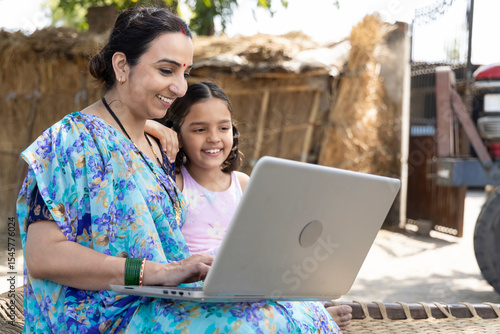 Tableau sur toile Happy mother with her daughter using laptop at village.