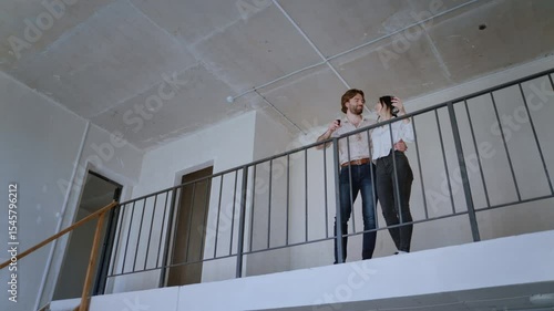 A happy couple shares a champagne toast on the balcony of their newly bought two-level unfurnished flat, complemented by a stylish chandelier inside