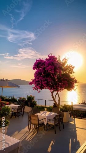 Wallpaper Mural Sunset view over the ocean from an outdoor dining terrace with pink bougainvillea tree and tables set with white cloths creating a vacation atmosphere. Torontodigital.ca