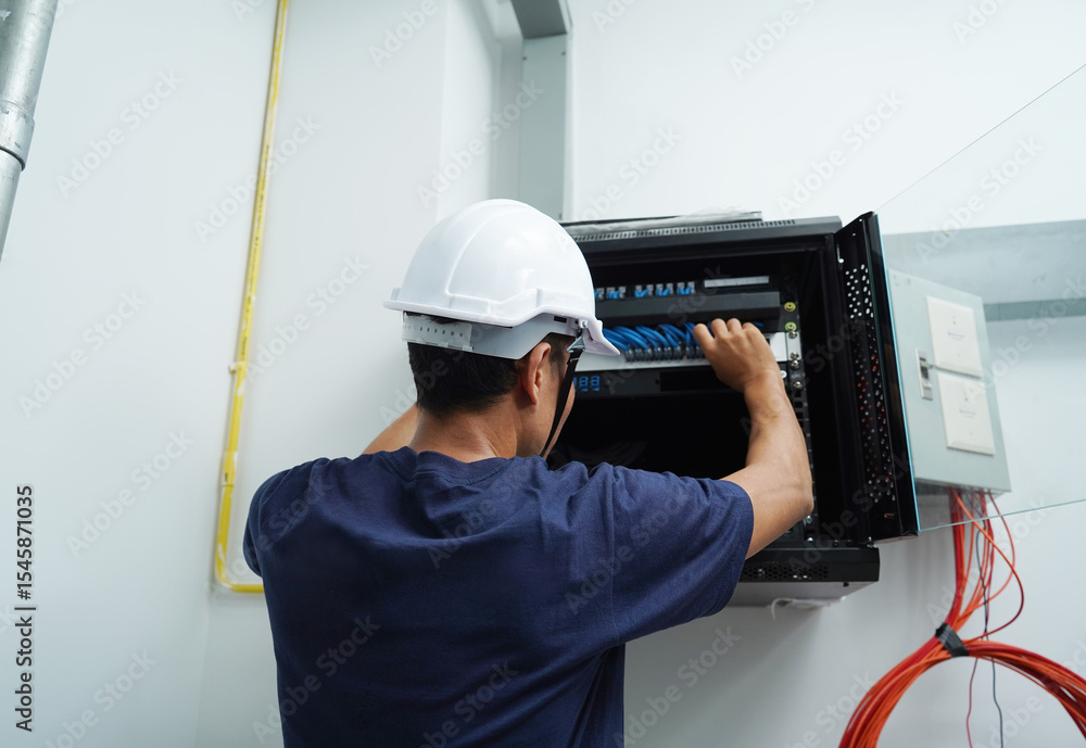 A maintenance technician works in a server room with a fiber optic hub A maintenance technician works in a server room with a fiber optic hub
