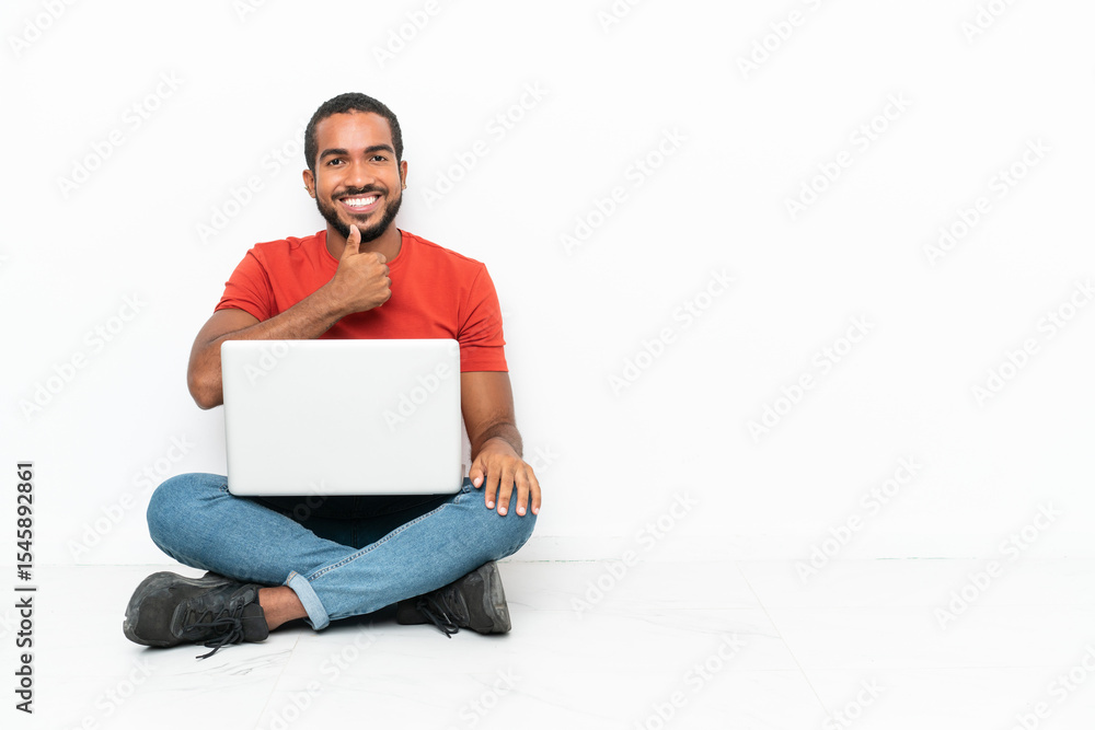 Young Ecuadorian man with a laptop sitting on the floor isolated on white background giving a thumbs up gesture Young Ecuadorian man with a laptop sitting on the floor isolated on white background giving a thumbs up gesture