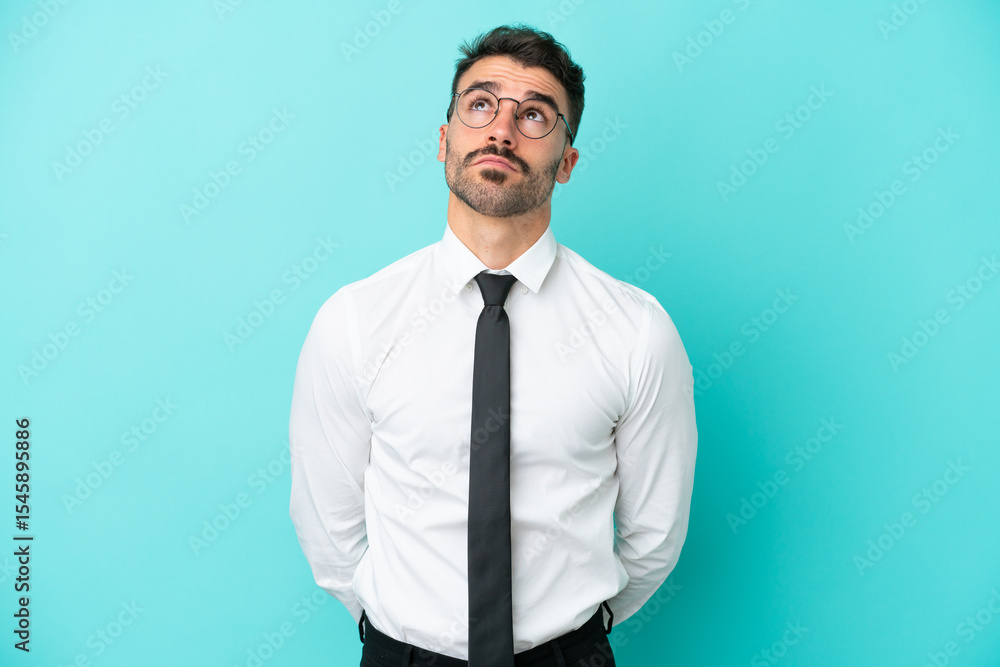 Business caucasian man isolated on blue background and looking up Business caucasian man isolated on blue background and looking up