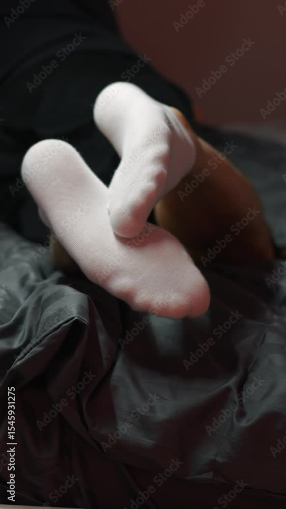 Man lying on bed in white socks.
Legs on gray background in bedroom in evening.
Relaxation on bed in socks Man lying on bed in white socks.
Legs on gray background in bedroom in evening.
Relaxation on bed in socks