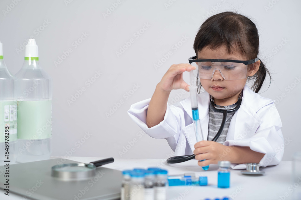 A young child in a lab coat and goggles carefully conducts an experiment with test tubes and beakers, embodying curiosity and scientific exploration. A young child in a lab coat and goggles carefully conducts an experiment with test tubes and beakers, embodying curiosity and scientific exploration.