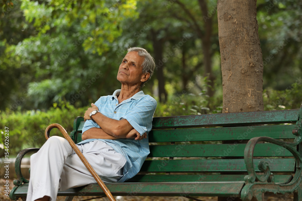 Fototapeta premium Indian old man spending leisure time at park after retirement