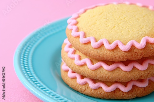 Colorful frosted cookies stacked on a decorative turquoise plate against a soft pink background creating a delightful and appealing dessert composition perfect for celebrations and joyful events