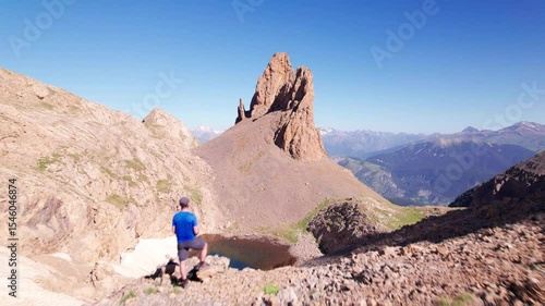 Solo hiker standing in awe before Agujas de Lavasar in the Pyrenees of Aragón, 4K aerial drone shot of rocky alpine terrain, dramatic solitude in the remote Chistau Valley, Spain

