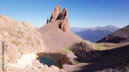Drone 4K video of Agujas de Lavasar and glacial Ibón de Lavasar, wild mountain scenery in Chistau Valley, Cotiella Massif, Pyrenees of Aragón, summer landscape with blue sky and no people
