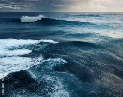 Ocean Wave Aerial: A high-angle view captures the grandeur of a dark blue sea, with powerful waves cresting and foaming under a stormy sky