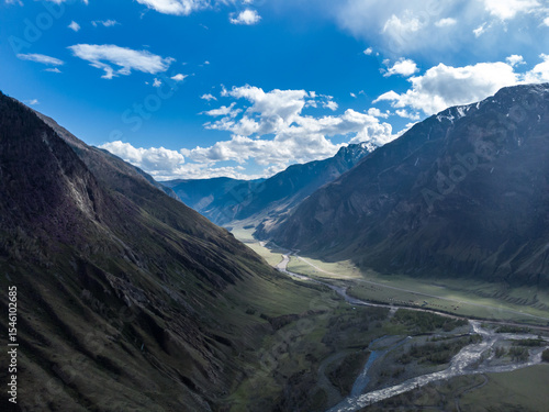 Scenic view of Chulyshman River Valley in Altai. lush green vegetation and towering mountains under cloudy sky. Travel and landscape photography.