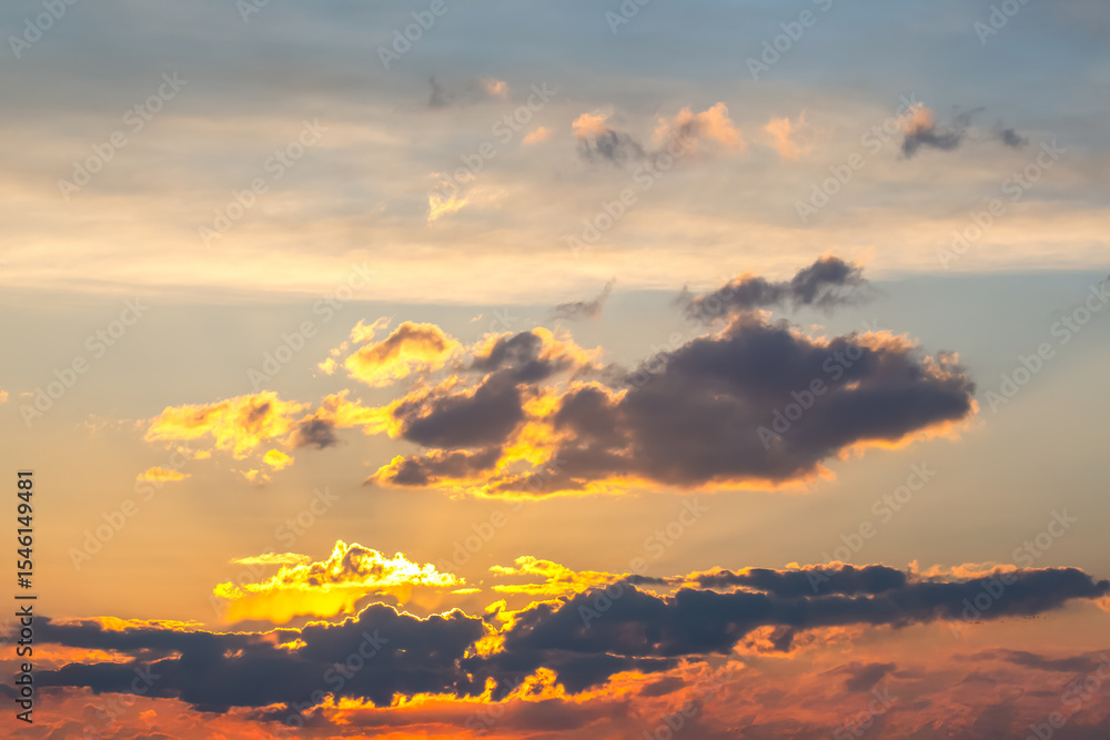 Fototapeta premium Beautiful sky at sunset with warm golden hues reflecting off scattered clouds. The mix of soft pastel colors and bold shadows makes for a peaceful and dreamy view.