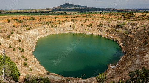 Panoramic view of the Tsar Asen Mine in Bulgaria – a former open-pit copper and non-ferrous metal mine, now a vivid turquoise lake set in a dramatic landscape of terraced rock layers.