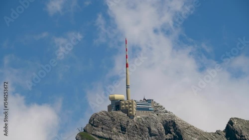 Tower on a mountain peak surrounded by clouds on a bright sunny day