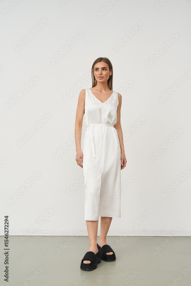 Beautiful female model poses in stylish white dress in indoor studio setting Beautiful female model poses in stylish white dress in indoor studio setting